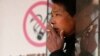 A man smokes in front of a "no smoking" sign outside a shopping mall in Shanghai, Jan. 10, 2014.