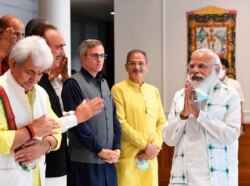 This photograph provided by the Prime Minister's Office shows Indian Prime Minister Narendra Modi, right, greeting members of various political parties before the start of their meeting in New Delhi, June 24, 2021.