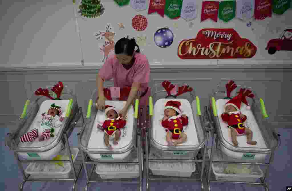 A nurse adjusts the outfits of newborn babies dressed in Santa costumes on Christmas eve at the Synphaet hospital in Bangkok, Thailand, Dec. 24, 2019.