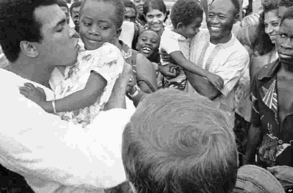 Muhammad Ali pose un baiser sur la joue d&#39;une jeune fille à son camp d&#39;entraînement de N&rsquo;Sele au Zaïre, le 26 octobre 1974. Ali vient de terminer son entrainement avant le son combat avec le champion poids lourd George Foreman à Kinshasa le 30 Octobre (AP Photo) 