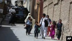 Families leaves their homes after a rocket strike in the western part of Kabul, Afghanistan, July 24, 2018. 