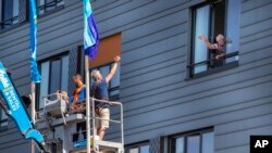 Pitrik van der Lubbe waves from a crane to his 88-year-old father Henk, right, at a nursing home in Gouda, Netherlands. (AP Photo/Peter Dejong)