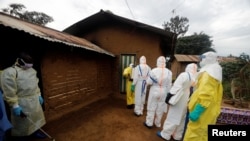 FILE - Kavota Mugisha Robert (L), a healthcare worker who volunteered in the Ebola response, stands with decontamination gear as his colleague prepare to enter a house where a woman, 85, is suspected of dying of Ebola, Eastern Congolese town of Beni.