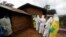 FILE - Kavota Mugisha Robert (L), a healthcare worker who volunteered in the Ebola response, stands with decontamination gear as his colleague prepare to enter a house where a woman, 85, is suspected of dying of Ebola, Eastern Congolese town of Beni.