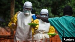 FILE - Medical staff working with Medecins sans Frontieres bring food to patients isolated at a treatment center in Kailahun, Sierra Leone, July 20, 2014.