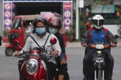 FILE - Motorists wear face masks to protect against the spread of the coronavirus in Phnom Penh, Cambodia, April 3, 2020.