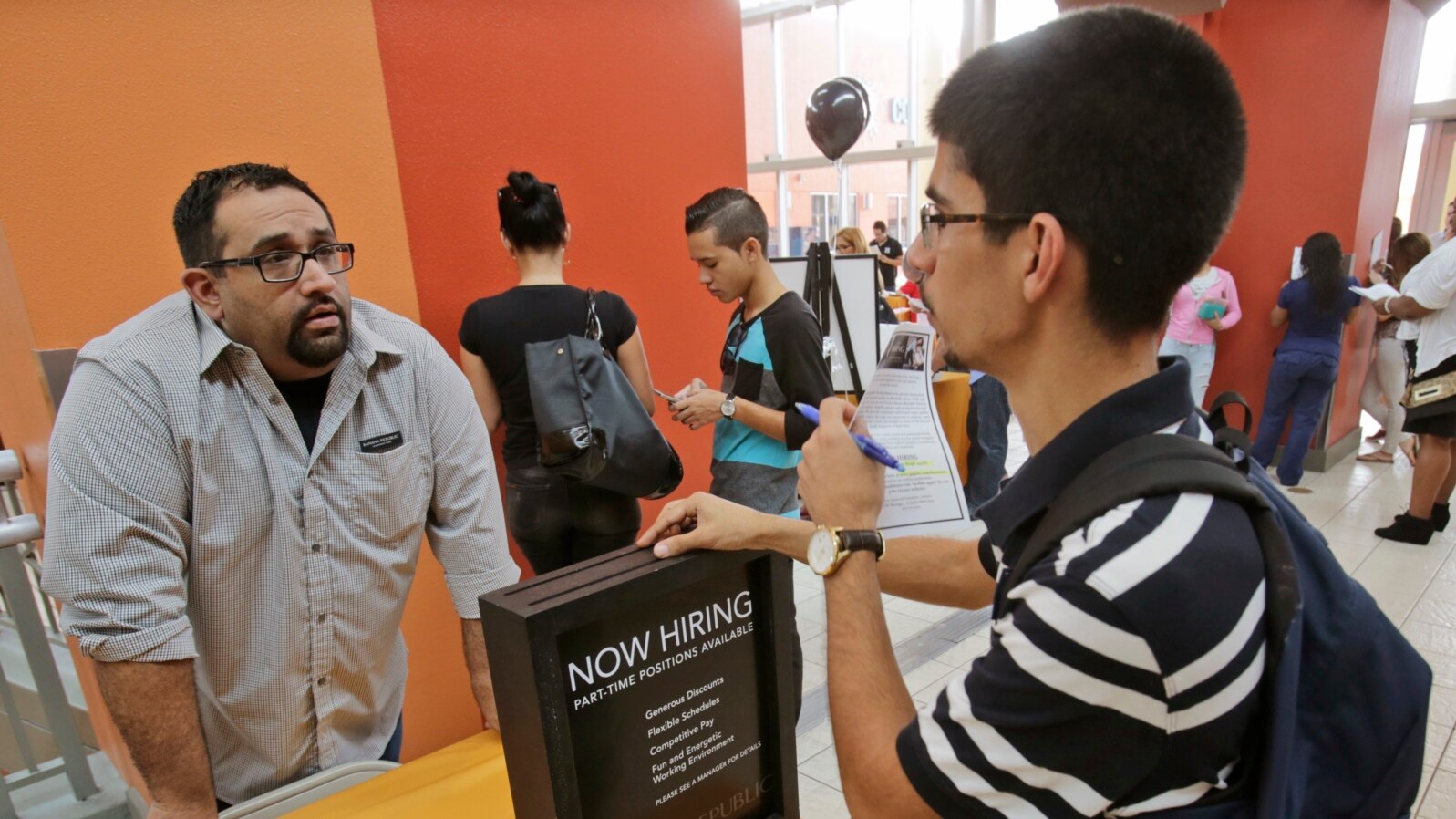 FILE - Job applicant Lazaro Fonte, right, 24, of Miami, talks with Banana Republic assistant manager Edward Ortega, during a job fair at Dolphin Mall in Miami. 