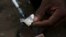 A syringe sucks up a mixture of heroin and water prepared on a foil wrap as addicts shoot up in Stone Town, Zanzibar, Dec. 2009 file photo.
