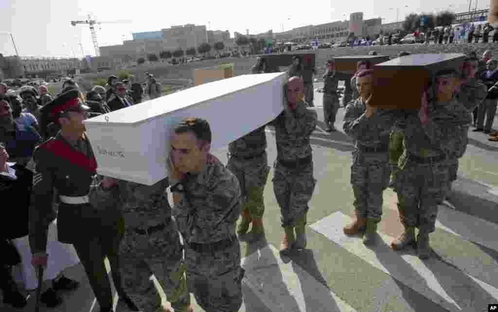 Men carry coffins during the funeral service for some of the 900 migrants who drowned while trying to reach the southern coast of Italy, on the outskirts of Valletta, Malta, April 23, 2015.