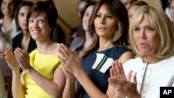 Amelie Derbaudrenghien, the partner of Belgian Prime Minister Charles Michel, left, U.S. first lady Melania Trump, center, and French first lady Brigitte Macron applaud during at the Queen Elisabeth Music Chapel in Waterloo, Belgium, July 11, 2018.