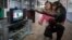 FILE - Zoo staff Sholpan Abdibekova and Tomiris, a five-year-old chimpanzee, react as they watch a BBC environmental program in a primate winter enclosure in Almaty, Kazakhstan, March 6, 2015. 