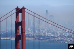 The San Francisco skyline is obscured by smoke from wildfires, as the Golden Gate Bridge rises in the foreground, Aug. 19, 2020, in this view from the Marin Headlands near Sausalito, Calif.