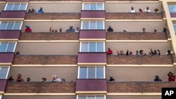 Les résidents confinés du quartier Hillbrow du centre-ville de Johannesburg sur leurs balcons le 27 mars 2020.