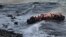 Refugees and migrants try to reach the shore on the Greek island of Lesbos, despite a rough sea, after crossing the Aegean Sea from Turkey, Oct. 30, 2015..
