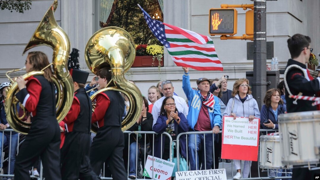 Viewers at the Columbus Day Parade wave a U.S. flag with Italian national colors and signs of expression, Oct. 14, 2019, in New York. 