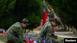 Soldiers sit near the graves sites of the fallen soldiers for a ceremony commemorating the 65th anniversary of the Second Taiwan Strait Crisis, in Kinmen, Taiwan, Aug. 23, 2023. 