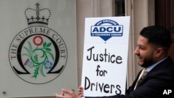 Un chófer de Uber posa con una cartel que pide "justicia para los conductores" frente a la Corte Suprema, en Londres, el 19 de febrero de 2021.