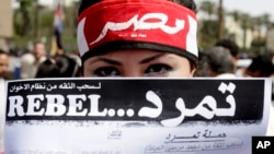 FILE - An Egyptian activist covers her face with an application for "Tamarod," Arabic for "rebel," a campaign calling for the ouster of Egyptian President Mohammed Morsi and for early presidential elections, during a protest in Tahrir Square, Cairo. 