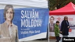 People walk past campaign tents of Moldova's incumbent President and presidential candidate Maia Sandu and presidential candidate Alexandr Stoianoglo in Chisinau, Moldova Oct. 30, 2024.