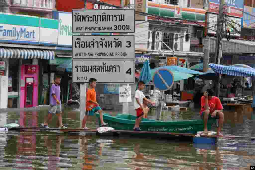 Boys cross a walkway in a flooded neighborhood, Ayutthaya, October 6, 2011. (VOA - D. Schearf)