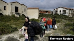 FILE PHOTO: Afghan refugees walk through a beach where they will wait to board a dinghy sailing off for the Greek island of Chios