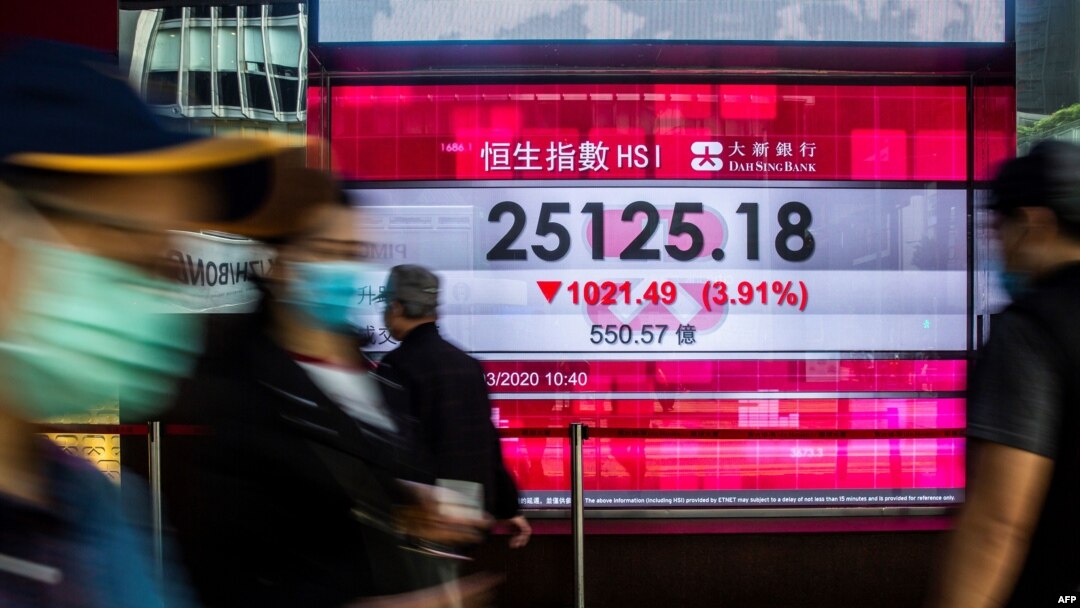 Pedestrians walk past an electronic sign displaying the Hang Seng Index in Hong Kong, March 9, 2020. Hong Kong stocks ended Monday's morning session sharply lower, in line with a rout across Asia, on coronavirus fears.
