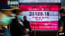 Pedestrians walk past an electronic sign displaying the Hang Seng Index in Hong Kong, March 9, 2020. Hong Kong stocks ended Monday's morning session sharply lower, in line with a rout across Asia, on coronavirus fears.