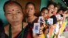 Indian voters pose for a photograph with their identity cards as they queue to cast their ballots in the state assembly elections at a polling station in Diphu in the Karbi Anglong district some 215 kms from Guwahati on April 4, 2016. 