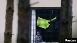 Un niño migrante observa desde la ventana de uno de los centros de detención de extranjeros en Bela-Jezova, República Checa.