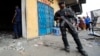 Un policier monte la garde devant un magasin pillé lors de violentes manifestations à Kinshasa, en République démocratique du Congo, 23 janvier 2015.