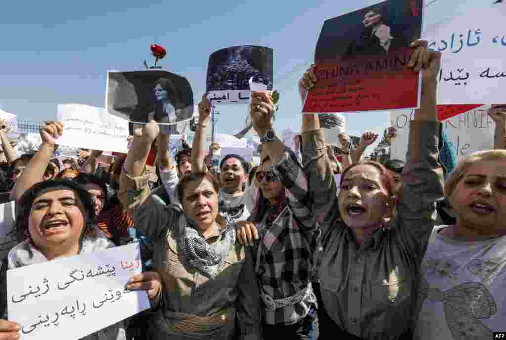 Di xwepêşandana Kurdên Îraq û Îranê ya li ber avahîya Neteweyên Yekbûyî a li Hewlêrê de, jin dirûşman berz dikin û wêneya Jîna Emînî hildigirin (24'ê Îlona 2022'an). AFP
