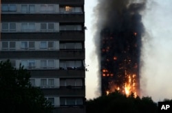 FILE - Smoke and flames rise from the Grenfell Tower in London, June 14, 2017. Police investigating a blaze that killed 72 people in a London tower block two years ago say no one is likely to face criminal charges until 2021.