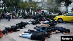 Demonstrators take cover from rubber bullets during a clash with the police while protesting against the amendment of the lese majeste law, in Bangkok, Thailand.