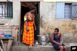 Justine Nangero, left, prepare a meal with her 11-year-old daughter, right, at their home in Kawempe tula village, Kampala, Uganda on Nov. 11, 2024. (AP Photo/Hajarah Nalwadda)