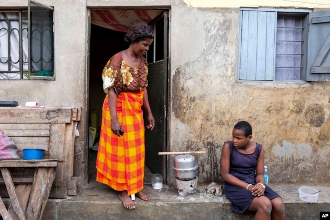 Justine Nangero, left, prepare a meal with her 11-year-old daughter, right, at their home in Kawempe tula village, Kampala, Uganda on Nov. 11, 2024. (AP Photo/Hajarah Nalwadda)