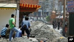 2009年7月8日，维吾尔人看着中国安全部队守在乌鲁木齐维族居住区的入口处