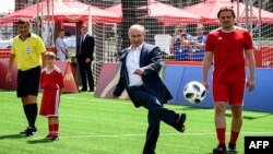 Le président russe Vladimir Poutine, au centre, donne le coup d'envoi à l'ouverture d'un match de football au Parc de la Coupe du monde sur la Place Rouge à Moscou le 28 juin 2018.