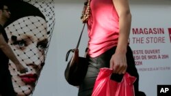 FILE - A shopper walks by a store in Paris, France.