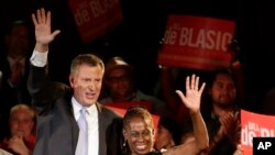 New York City Democratic Mayoral candidate Bill De Blasio, left, and his wife Chirlane wave to supporters at De Blasio election headquarters after polls closed in the city's primary election, Sept. 11, 2013, in New York. 