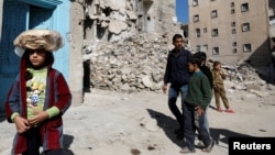 A girl carries a stack of bread on her head as she walks near rubble of damaged buildings in Aleppo's Kalasa district, Syria, April 12, 2019.