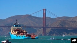 FILE - In this Sept. 8, 2018 photo, a ship tows The Ocean Cleanup's buoyant trash-collecting device toward the Golden Gate Bridge en route to the Pacific Ocean. The floating device is designed to catch plastic waste. 