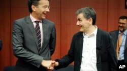 FILE - Dutch Finance Minister and chairman of the eurogroup Jeroen Dijsselbloem, left, shakes hands with Greek Finance Minister Euclid Tsakalotos during a meeting of eurozone finance ministers at the EU Council building in Brussels, Aug. 14, 2015.