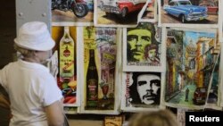 FILE -Tourists look at artwork based on images of revolutionary leader Che Guevara at an artisans' fair in Havana. 