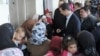 Syria&#39;s President Bashar al-Assad (C) speaks with women during his visit to displaced Syrians in the town of Adra in the Damascus countryside March 12, 2014, in this handout photograph released by Syria&#39;s national news agency SANA. State television said A