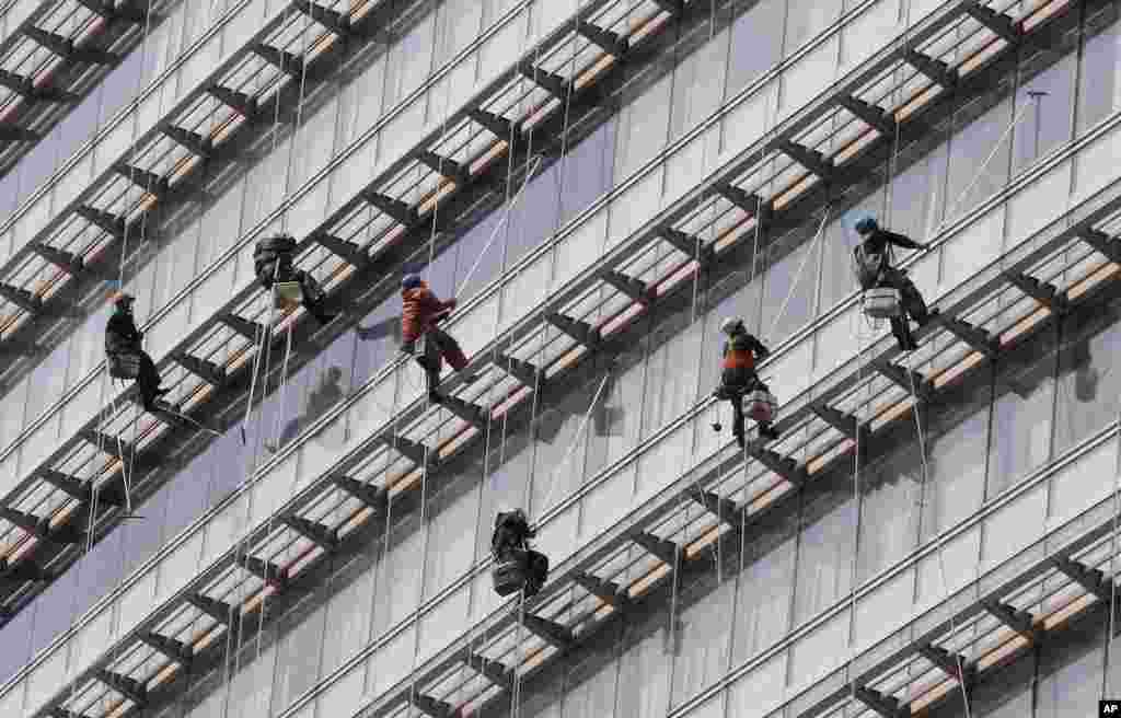 Workers clean windows of an office building in Seoul, South Korea.