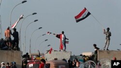 Para pengunjuk rasa anti-pemerintah Irak mengambil kendali atas tembok beton dan penghalang yang dilakukan pasukan keamanan, Baghdad, Irak, Kamis, 31 Oktober 2019. (Foto: AP / Hadi Mizban)