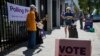 Para relawan berbicara dengan para pemilih di tempat pemungutan suara di Redfern pada pelaksanaan referendum mengenai hak-hak suara masyarakat adat, di Sydney, Australia, Sabtu, 14 Oktober 2023. (Foto: Rick Rycroft/AP Photo)