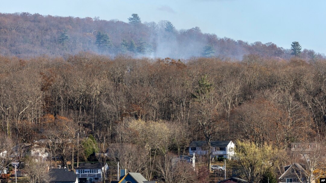 Humo de un incendio forestal se eleva detrás de una hilera de casas en la localidad de Awosting, vistas desde el otro extremo del lago Greenwood, el lunes 11 de noviembre de 2024, en Lakeside, Nueva Jersey. AP