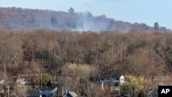 Humo de un incendio forestal se eleva detrás de una hilera de casas en la localidad de Awosting, vistas desde el otro extremo del lago Greenwood, el lunes 11 de noviembre de 2024, en Lakeside, Nueva Jersey. AP