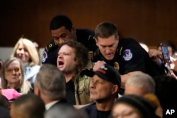 A protester is removed during a U.S. Senate Armed Services Committee confirmation hearing for Pete Hegseth, President-elect Donald Trump's choice to be defense secretary, at the Capitol in Washington on Jan. 14, 2025.